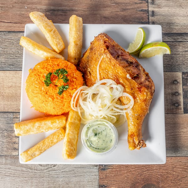 Cuban roasted chicken with yellow rice, yuca fries, sliced onions, lime, and green sauce.