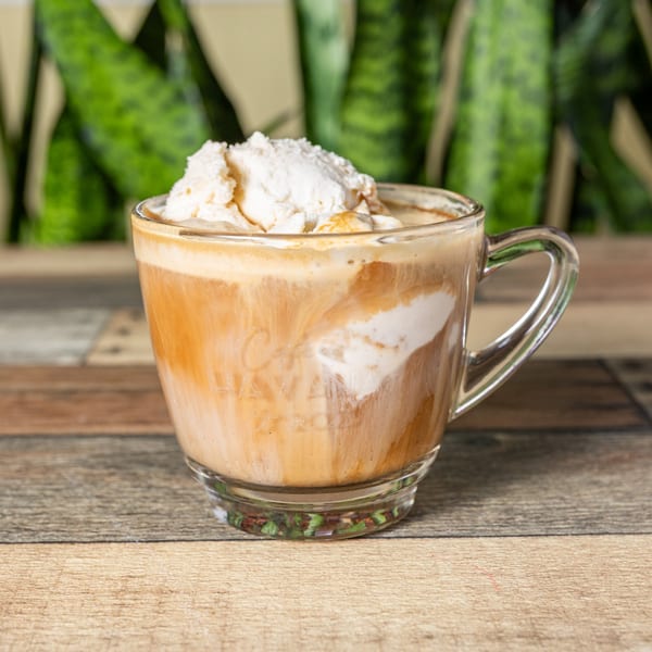 Cuban coffee with a scoop of vanilla ice cream in a clear mug on a wooden table.